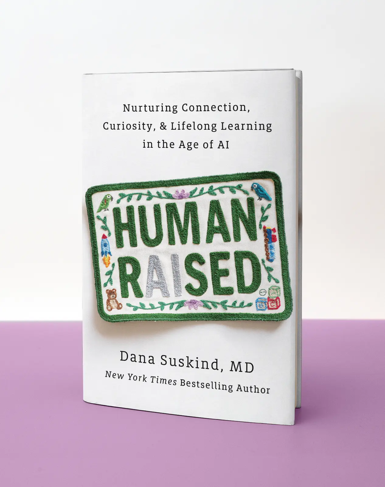 Human Raised hardcover pack shot on pink and white background